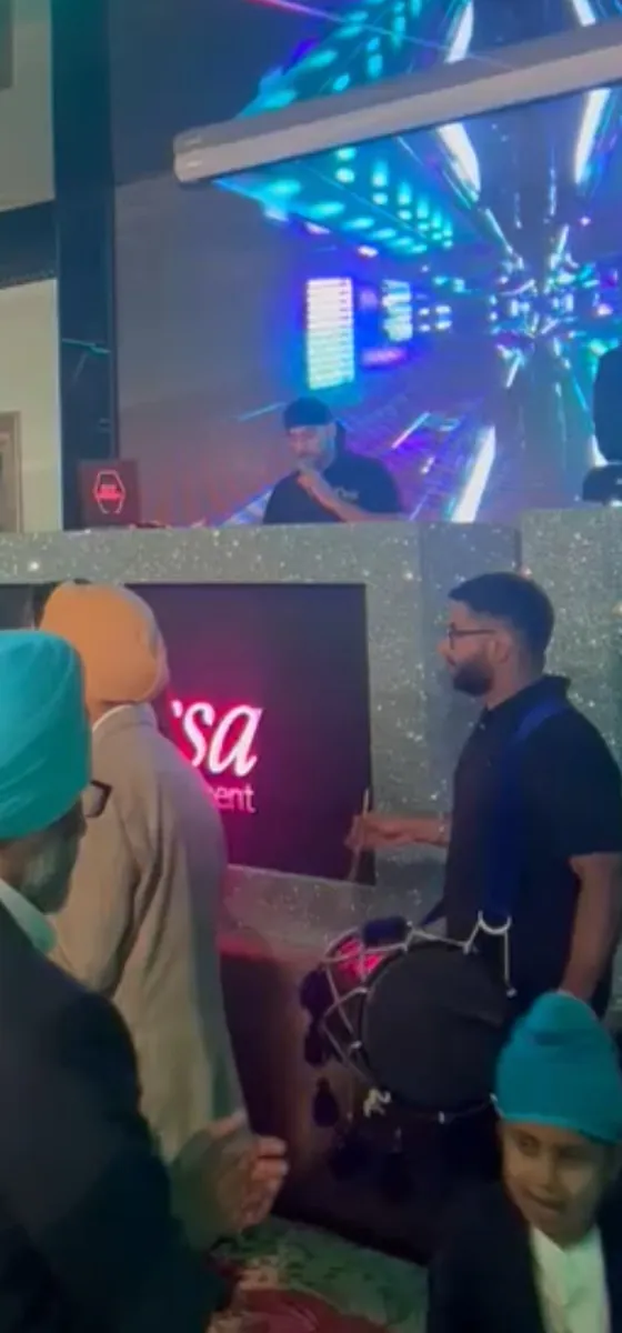 Manraj on dhol in front of a glittering DJ booth