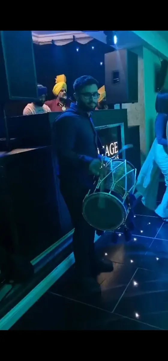 Manraj playing dhol on a starlit dancefloor under blue lighting