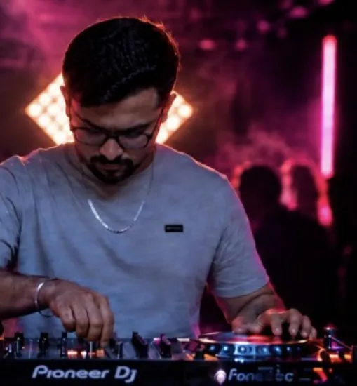 DJ Manraj mixing on Pioneer DJ decks under pink club lighting