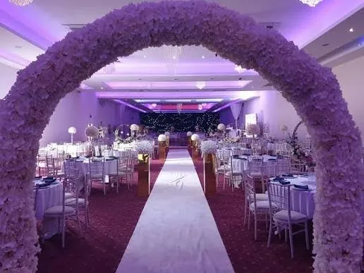 A blossom arch over the aisle at Brooklands Suite under purple uplighting